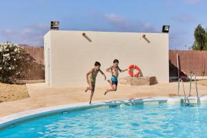 two young boys jumping into a swimming pool at TAIGA Almeria Playa in Palomares