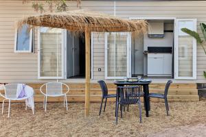 a table and chairs under a straw umbrella at TAIGA Almeria Playa in Palomares