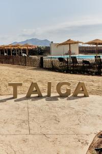 a sign on a beach with umbrellas and a pool at TAIGA Almeria Playa in Palomares
