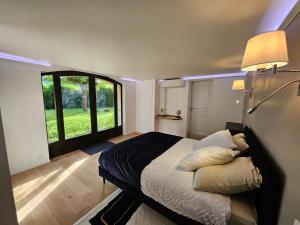 a bedroom with a bed and a large window at Charmante Maisonette du Lot rénovée avec balnéo in Latouille-Lentillac