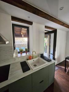 a kitchen with a sink and two windows at Charmante Maisonette du Lot rénovée avec balnéo in Latouille-Lentillac +26 photos