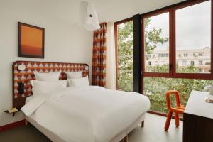 una camera da letto con un letto bianco e una finestra di Edgar Suites Montrouge a Montrouge