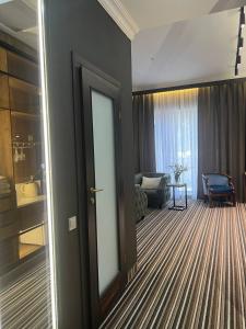 a room with a door and a living room with a chair at Sapar Standart Hotel LUXE Люкс из двух комнат in Shymkent