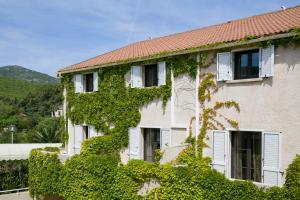 an ivy covered building with white windows and white shutters at Hotel U Ricordu & Spa in Macinaggio