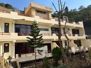 a large building with a tree in front of it at Couple friendly Deluxe Rooms Kasauli Hills Kumarhatti in Dagshai