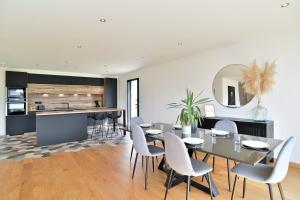 a dining room with a table and chairs and a kitchen at Cosy Fréhel - Maison moderne proche du bourg in Frehel +7 photos