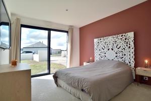 a bedroom with a large bed and a large window at Cosy Fréhel - Maison moderne proche du bourg in Frehel