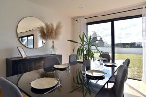 a dining room with a table and a mirror at Cosy Fréhel - Maison moderne proche du bourg in Frehel