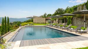 Una piscina con sillas y sombrillas en un patio trasero. en VILLA KRISZTINA 10, Emma Villas, en Bagnone