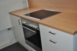 a kitchen with a stove and a wooden counter top at Gästedorf Waldheimat in Langenwang