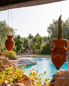 - une piscine avec deux vases suspendus à une terrasse couverte dans l'établissement Masseria Le Lamie, à Villa Castelli