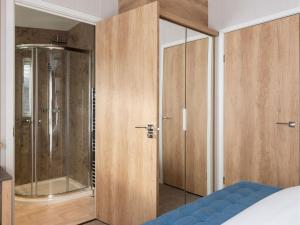 a bedroom with a glass shower and a bed at Pinewoods Saltmarsh Lodge sleeps 7 – no.1 in Wells next the Sea +2 photos