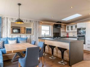 a kitchen and living room with a table and a blue couch at Pinewoods Saltmarsh Lodge no.2 sleeps 7 – no dogs in Wells next the Sea