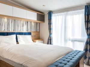 a bedroom with a large bed with blue curtains at Pinewoods Saltmarsh Lodge no.2 sleeps 7 – no dogs in Wells next the Sea