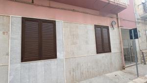 a building with brown shutters on the side of it at Vititta Appartamenti in Trapani