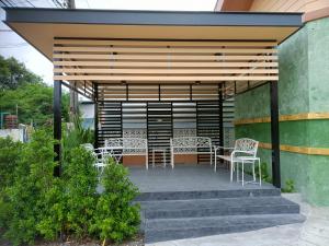 a patio with chairs and tables and a wooden pergola at เซฟเฮ้าส์ รีสอร์ท in Pattani