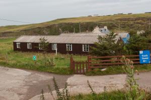 a house on the side of a hill with a fence at Durness Youth Hostel in Durness