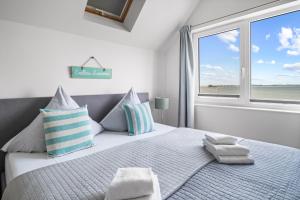 a white bedroom with a large bed with a window at Ferienwohnung Große Freiheit Olpenitz in Olpenitz