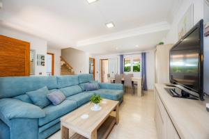 a living room with a blue couch and a tv at Casa Paraiso de Alcudia in Port d'Alcudia