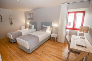 a bedroom with two beds and a table and a desk at Palácio dos Marqueses in Mafra
