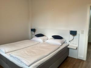 un letto con lenzuola bianche e cuscini blu sopra di Ferienwohnung am Hotel am Rathaus a Schönberg