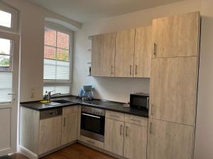 una cucina con armadi in legno e piano di lavoro nero di Ferienwohnung am Hotel am Rathaus a Schönberg