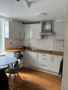 a kitchen with white cabinets and a table and a sink at Central quality point piccadilly in London