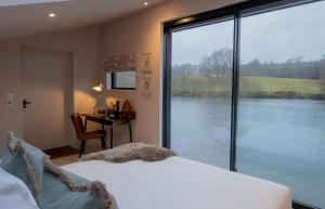 a bedroom with a large window looking out onto a lake at Leeds Castle Lakeside Lodges in Broomfield