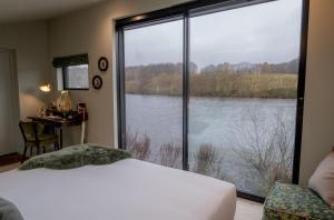 a bedroom with a large window with a view of a lake at Leeds Castle Lakeside Lodges in Broomfield