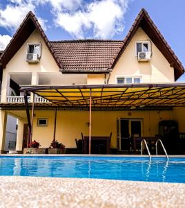 a house with a swimming pool in front of a house at Pensiunea Vila Silva I in Haţeg