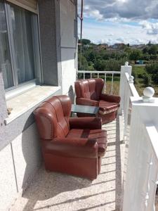 two leather chairs and a table on a balcony at Acogedora casita de campo in Bóveda