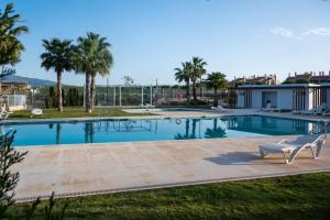 a swimming pool with two chairs and palm trees at Casa Cariño @ Hacienda del Alamo Golf resort in Fuente Alamo