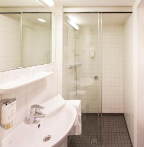 ein weißes Bad mit einem Waschbecken und einer Dusche in der Unterkunft Stadthotel am Römerturm in Köln