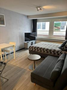 Un dormitorio con una cama, un sofá y una mesa. en Entourage Christinastraat, en Ostende