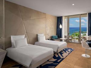 a hotel room with two beds and a view of the ocean at Swissôtel Resort Bodrum Beach in Turgutreis