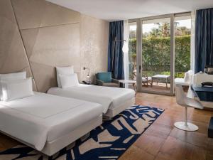 a hotel room with two beds and a balcony at Swissôtel Resort Bodrum Beach in Turgutreis