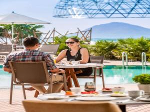 a man and woman sitting at a table by a pool at Swissôtel Resort Bodrum Beach in Turgutreis