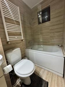 a bathroom with a toilet and a bath tub at Oly Apartment in Năvodari