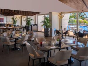 a restaurant with tables and chairs and a pool at Swissôtel Resort Bodrum Beach in Turgutreis