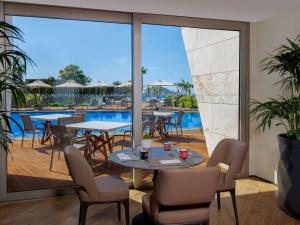 a restaurant with tables and chairs and a pool at Swissôtel Resort Bodrum Beach in Turgutreis
