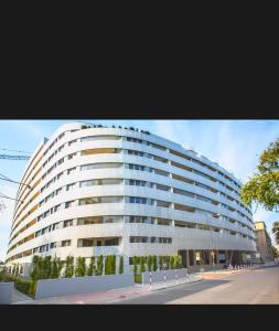 a large white building with trees in front of it at Prime Browary Apartment in Warsaw