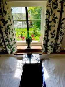 a bedroom with a window with a vase on a table at Adagio på Österlen in Kivik +23 photos