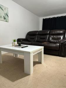 ein Wohnzimmer mit einem schwarzen Ledersofa und einem weißen Couchtisch in der Unterkunft Winstanley Stay in Chesterton