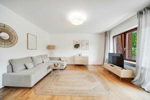 a white living room with a couch and a tv at Chiemsee Ferienwohnung Gartenblick in Prien am Chiemsee