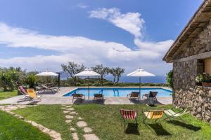 a pool with chairs and umbrellas next to a building at Casale La Torre Luxury by Feeling Italy in Massa Lubrense