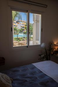 Schlafzimmer mit einem Fenster und Poolblick in der Unterkunft Vista Calanova Golf Club Apartment, 2BD Seaviews in La Cala de Mijas