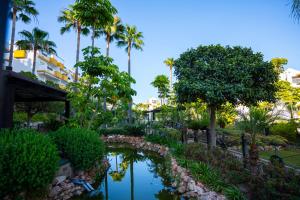 einen Garten mit einem Teich und Palmen in der Unterkunft Vista Calanova Golf Club Apartment, 2BD Seaviews in La Cala de Mijas