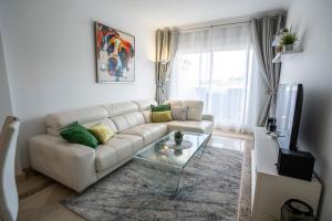 ein Wohnzimmer mit einer weißen Couch und einem Glastisch in der Unterkunft Vista Calanova Golf Club Apartment, 2BD Seaviews in La Cala de Mijas