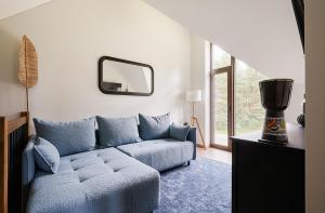ein Wohnzimmer mit einem blauen Sofa und einem Spiegel in der Unterkunft Kotedžas prie jūros in Palanga