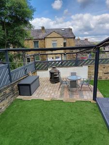 a patio with a grill and a table and chairs at The Happy House in Huddersfield